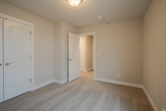 unfurnished bedroom with a textured ceiling, light colored carpet, and a closet