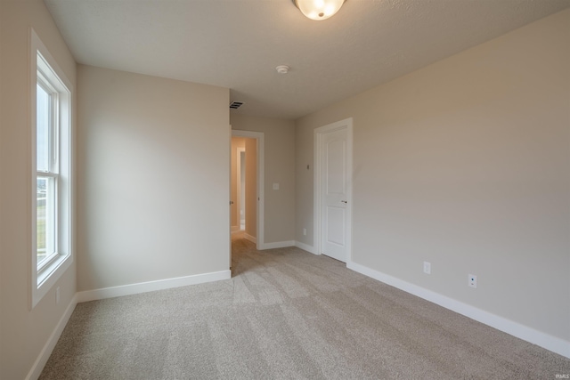 spare room featuring light colored carpet and plenty of natural light