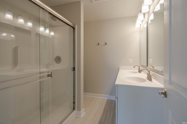 bathroom with a shower with door, vanity, wood-type flooring, and a textured ceiling