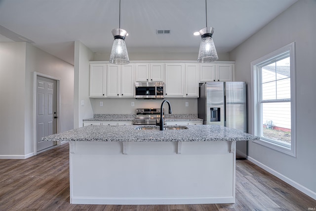 kitchen with white cabinets, decorative light fixtures, sink, and stainless steel appliances