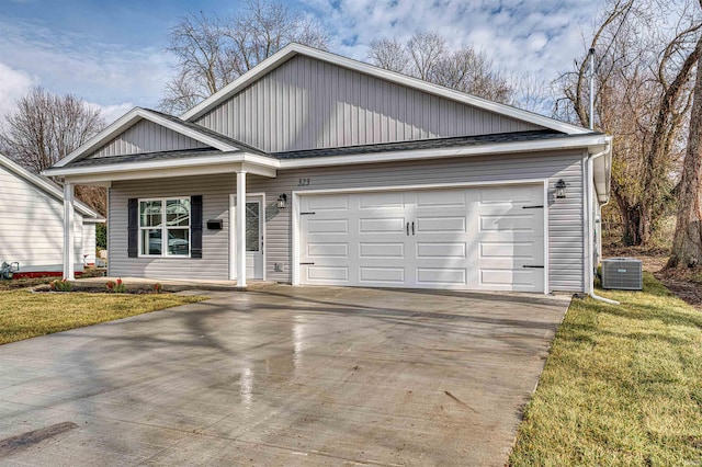 view of front facade with a garage, central air condition unit, and a front lawn