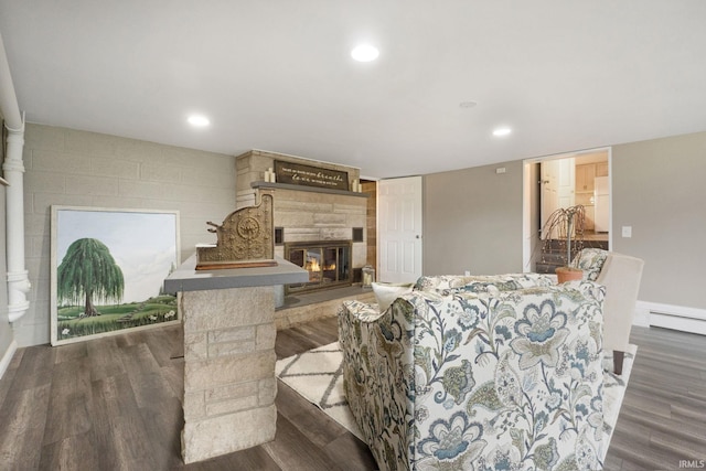 living room with a fireplace, dark wood-type flooring, and a baseboard heating unit