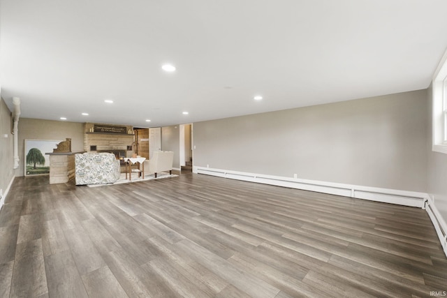 unfurnished living room featuring a stone fireplace, light hardwood / wood-style floors, and a baseboard heating unit