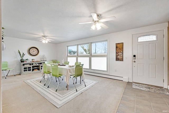 tiled dining space featuring baseboard heating, ceiling fan, and a textured ceiling