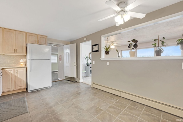 kitchen with a baseboard heating unit, white refrigerator, ceiling fan, light brown cabinetry, and tasteful backsplash