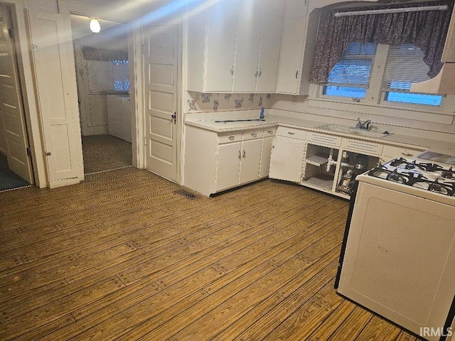 kitchen featuring white cabinets, hardwood / wood-style floors, sink, and gas range gas stove