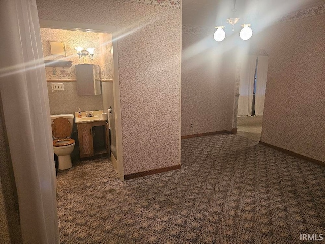 bathroom with sink, a notable chandelier, and toilet