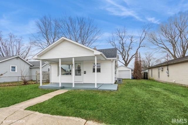 back of property with an outbuilding, central AC, covered porch, a garage, and a lawn