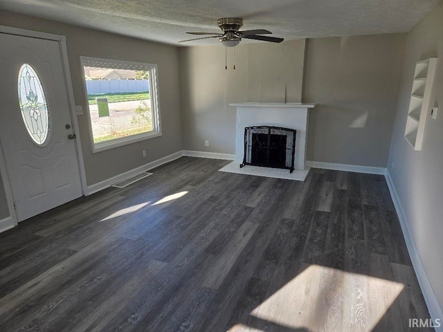 unfurnished living room featuring ceiling fan, dark hardwood / wood-style flooring, and a textured ceiling