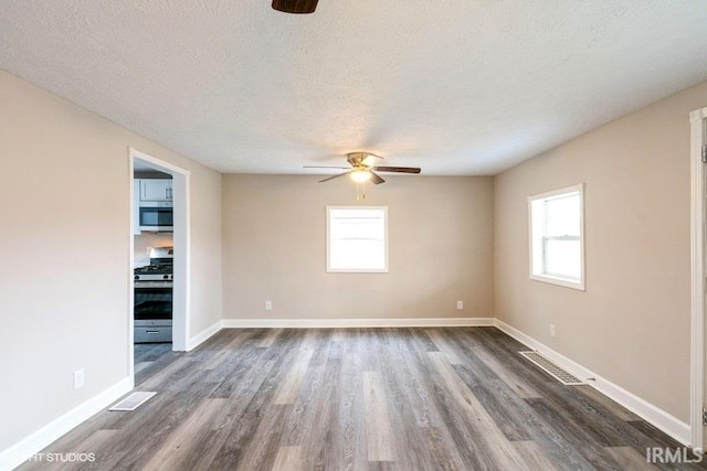 spare room with plenty of natural light, dark hardwood / wood-style floors, a textured ceiling, and ceiling fan