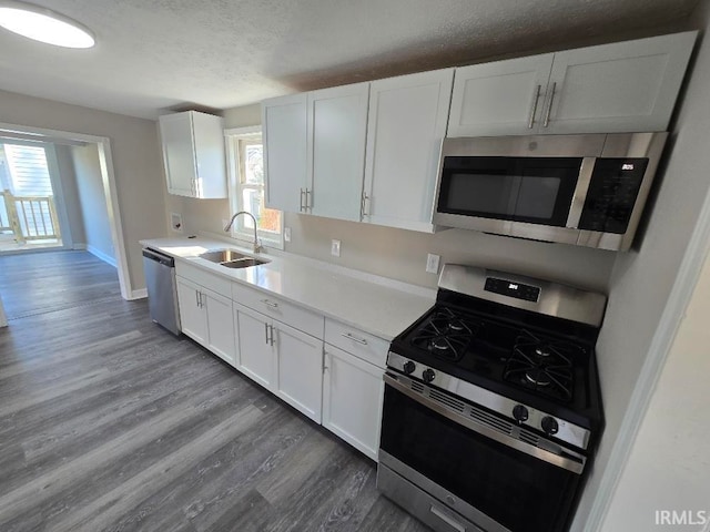 kitchen featuring sink, stainless steel appliances, dark hardwood / wood-style flooring, a textured ceiling, and white cabinets