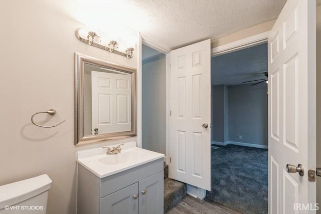 bathroom featuring ceiling fan, toilet, a textured ceiling, and vanity