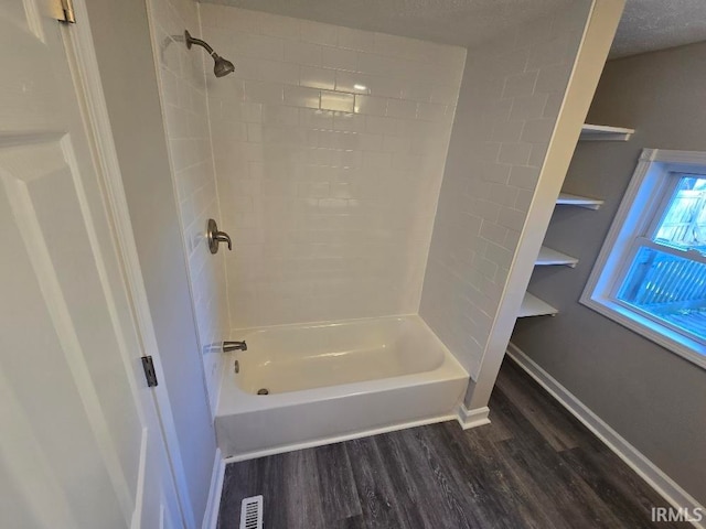 bathroom featuring wood-type flooring, a textured ceiling, and shower / bath combination