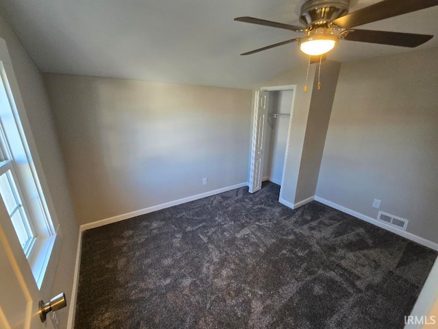 unfurnished bedroom with ceiling fan, dark carpet, lofted ceiling, and a closet