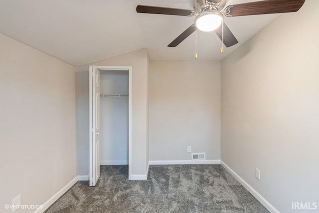 unfurnished bedroom featuring dark colored carpet, a closet, vaulted ceiling, and ceiling fan