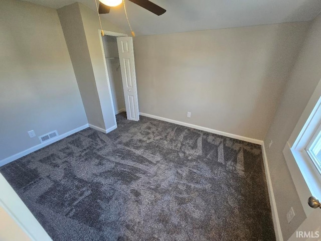 unfurnished bedroom with dark carpet, ceiling fan, and lofted ceiling