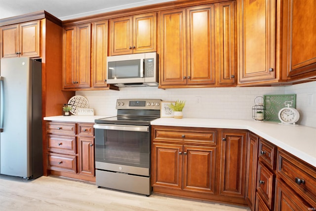 kitchen featuring decorative backsplash, appliances with stainless steel finishes, and light hardwood / wood-style flooring