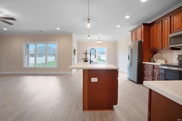 kitchen with pendant lighting, backsplash, a kitchen island with sink, sink, and appliances with stainless steel finishes