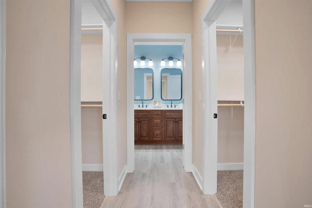 hallway with light hardwood / wood-style floors and sink