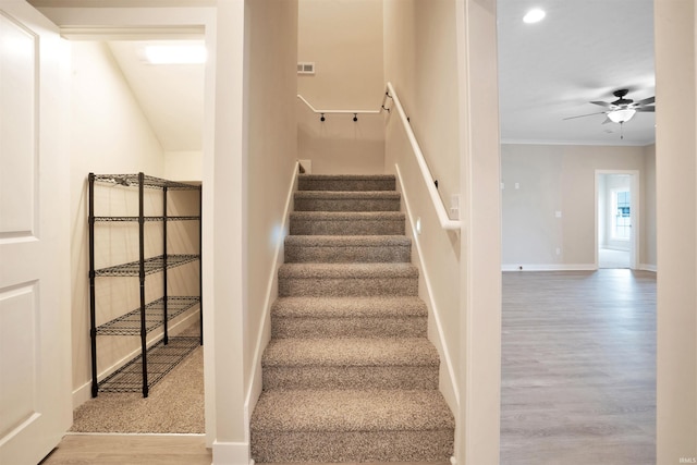 stairway featuring ceiling fan, ornamental molding, and hardwood / wood-style flooring