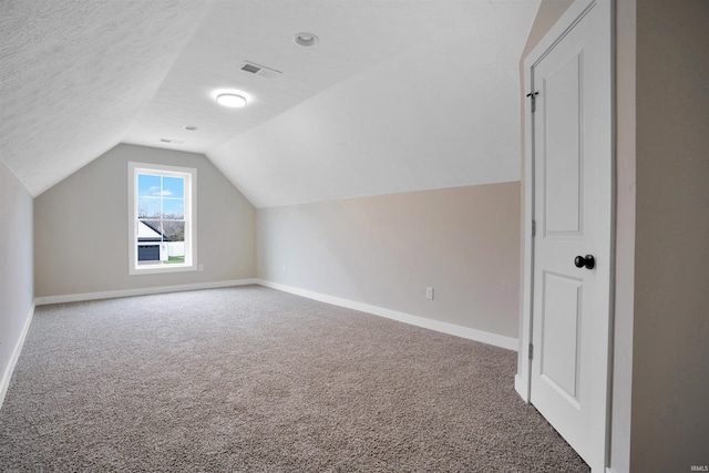 additional living space featuring a textured ceiling, carpet, and lofted ceiling