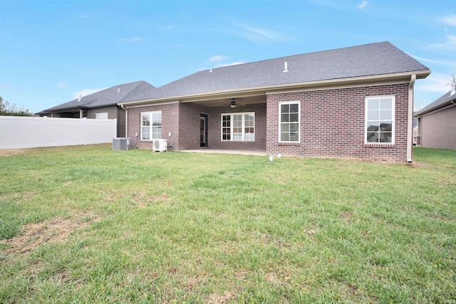 rear view of property featuring ceiling fan, cooling unit, a patio area, and a lawn