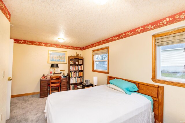 bedroom with light colored carpet and a textured ceiling