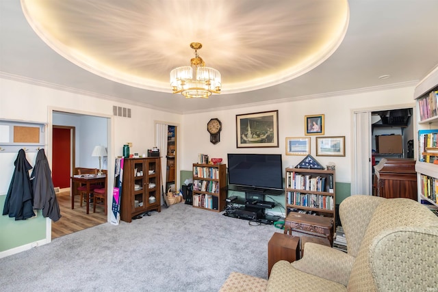 living room with a chandelier, carpet floors, a tray ceiling, and crown molding