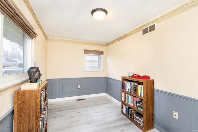 sitting room with crown molding and light hardwood / wood-style flooring