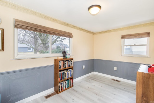 empty room featuring light wood-type flooring and ornamental molding