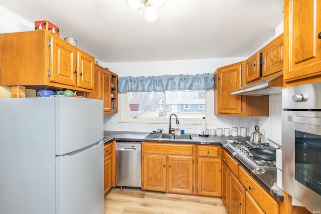 kitchen featuring light wood-type flooring, sink, appliances with stainless steel finishes, and tasteful backsplash