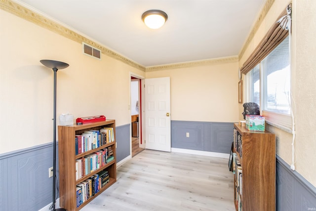 interior space with ornamental molding and light hardwood / wood-style flooring