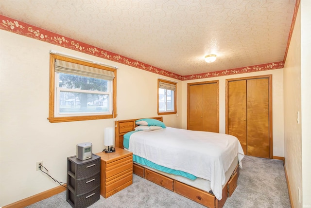 carpeted bedroom with multiple closets and a textured ceiling