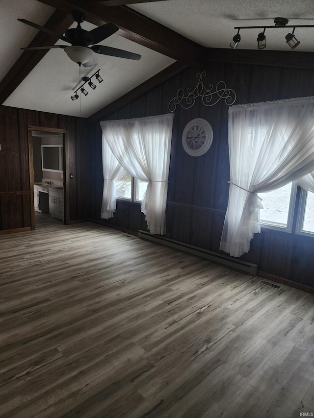 interior space with vaulted ceiling with beams, wood-type flooring, a textured ceiling, and track lighting