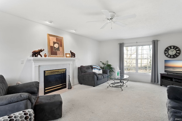 living room featuring a tiled fireplace, ceiling fan, and carpet