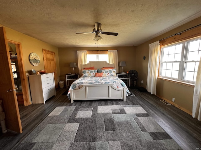 bedroom featuring multiple windows, ceiling fan, dark hardwood / wood-style floors, and a textured ceiling