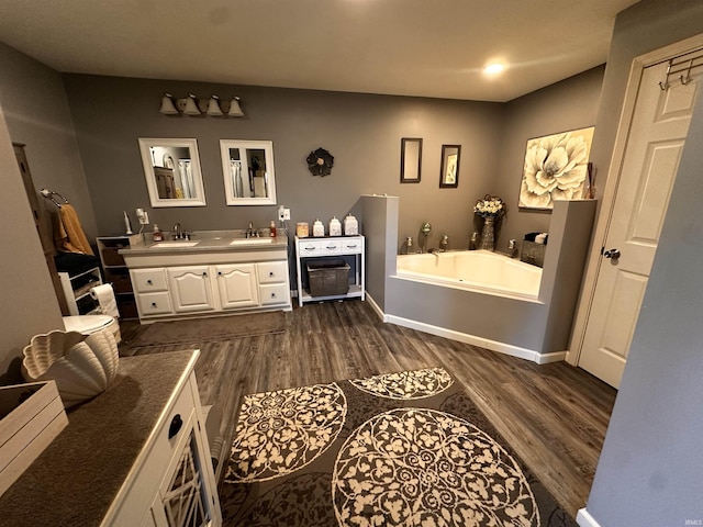 bathroom with hardwood / wood-style flooring, vanity, and a bath