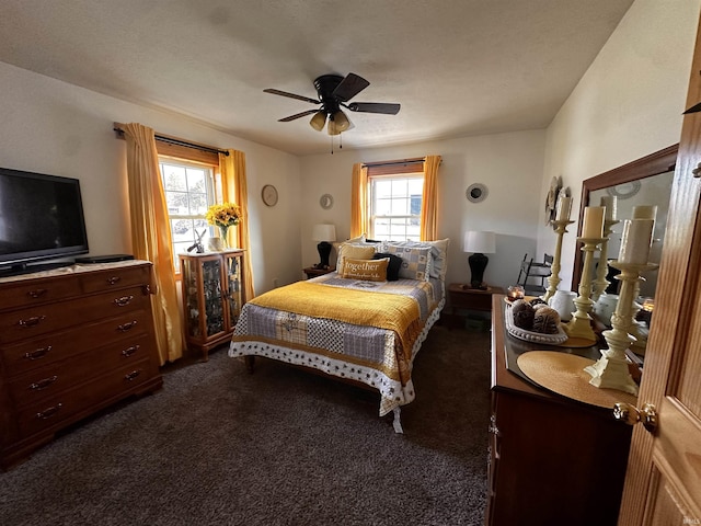 bedroom with ceiling fan, dark carpet, and multiple windows