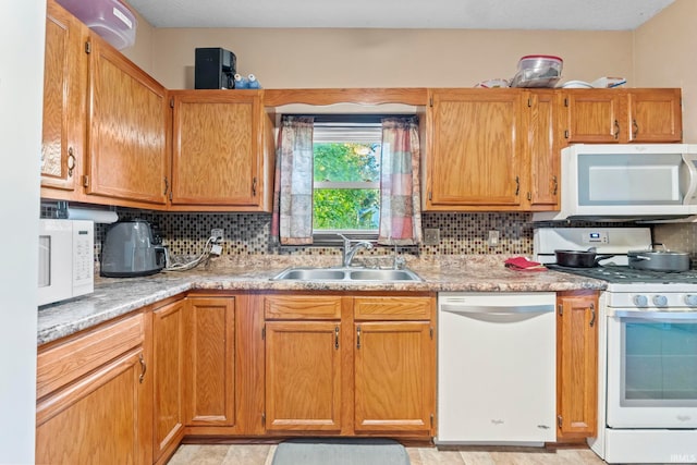 kitchen featuring decorative backsplash, sink, light stone counters, and white appliances