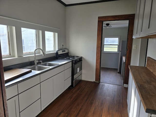 kitchen with dark hardwood / wood-style flooring, sink, white cabinetry, and stainless steel gas range