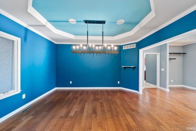 unfurnished room with hardwood / wood-style floors, a raised ceiling, and ornamental molding