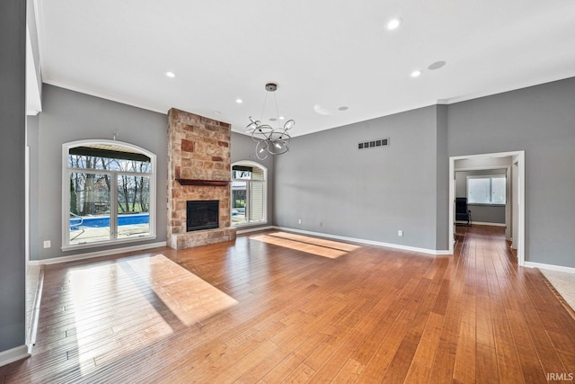 unfurnished living room featuring crown molding, a chandelier, a fireplace, and hardwood / wood-style floors