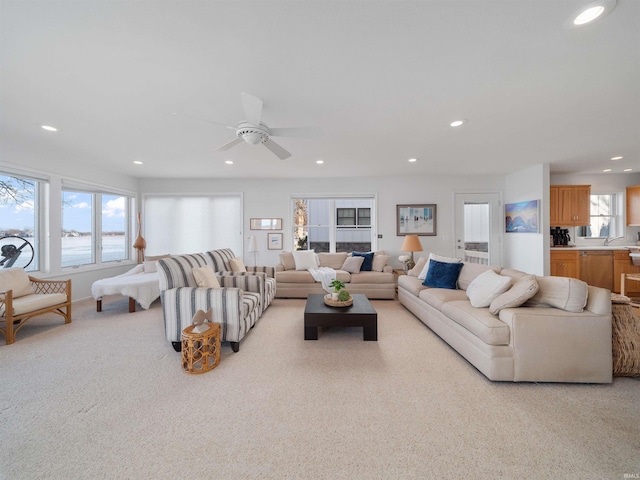 living room featuring light carpet, a water view, and ceiling fan