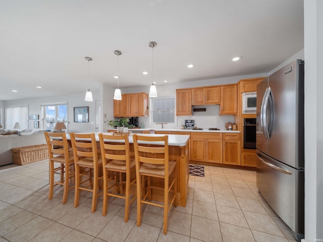 kitchen with a kitchen bar, appliances with stainless steel finishes, light tile patterned floors, a kitchen island, and hanging light fixtures