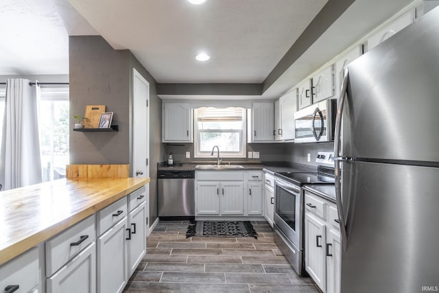 kitchen featuring a wealth of natural light, white cabinetry, sink, butcher block countertops, and appliances with stainless steel finishes