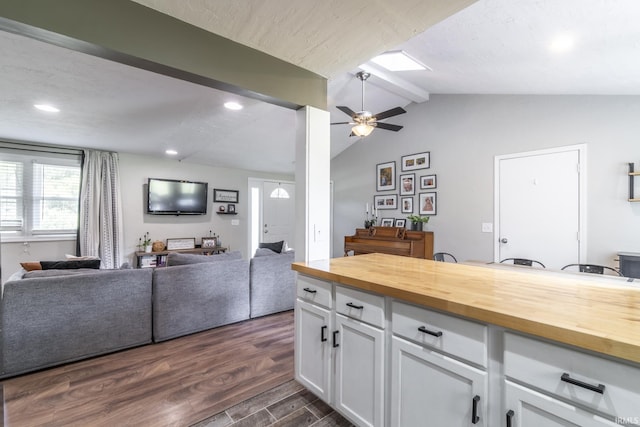 kitchen featuring wood counters, ceiling fan, dark wood-type flooring, vaulted ceiling with beams, and white cabinetry