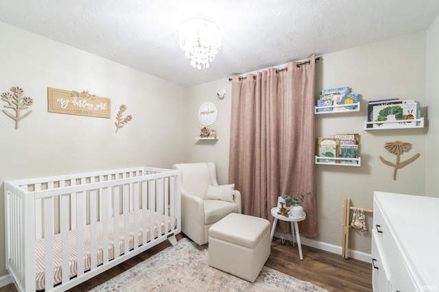 bedroom with hardwood / wood-style floors, an inviting chandelier, and a nursery area