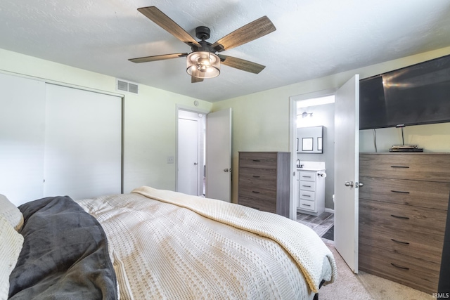 bedroom featuring light carpet, ceiling fan, sink, connected bathroom, and a closet