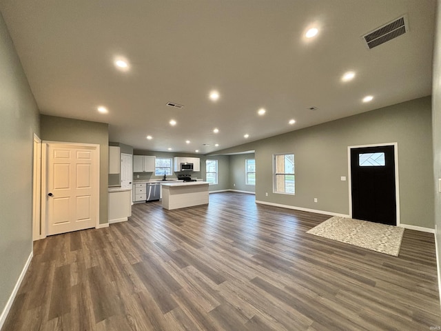 kitchen with a center island, stainless steel appliances, white cabinetry, and dark wood-type flooring