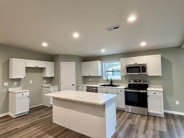 kitchen with dark hardwood / wood-style flooring, stainless steel appliances, sink, white cabinetry, and a kitchen island